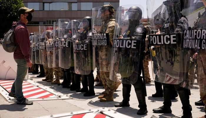 Um homem enfrenta membros das forças de segurança em frente ao edifício federal Edward R. Royb...